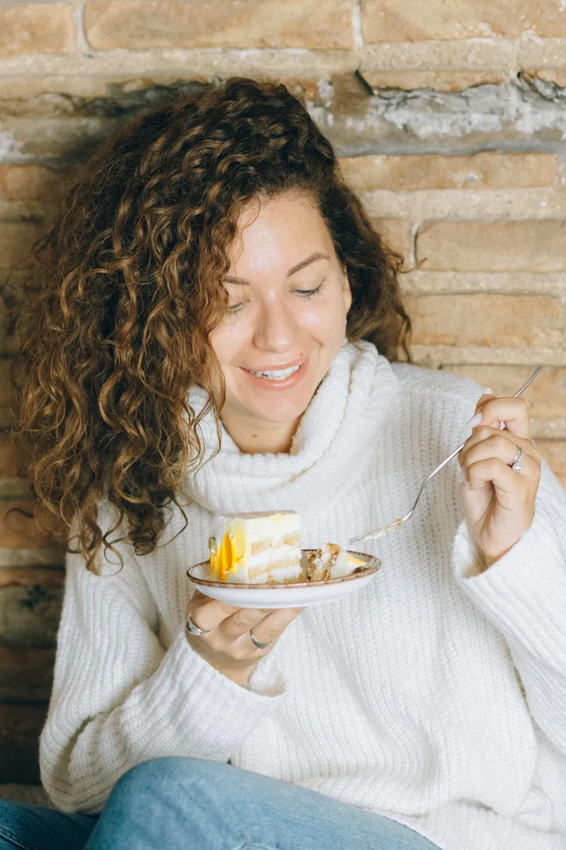 Woman in a cosy sweater enjoying a slice of cake