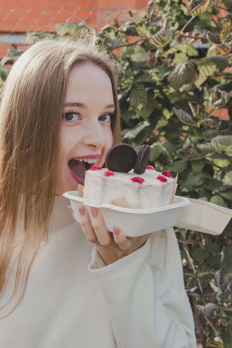 Young woman holding a decorated cake outdoors